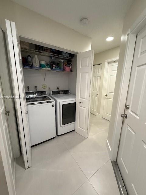 clothes washing area featuring light tile patterned floors and independent washer and dryer