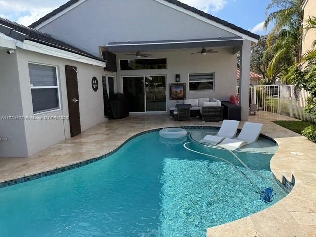 view of swimming pool featuring outdoor lounge area, a patio, and ceiling fan