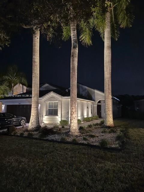 property exterior at night with a lawn