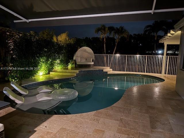 pool at night featuring a patio area