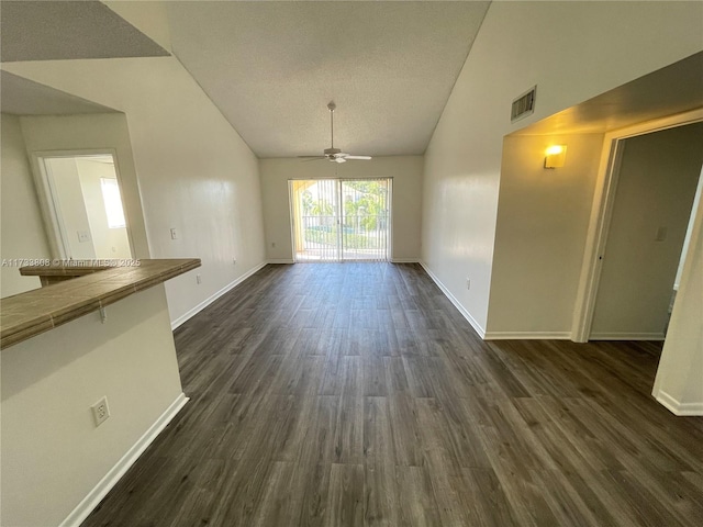 interior space with a textured ceiling, vaulted ceiling, dark hardwood / wood-style floors, and ceiling fan