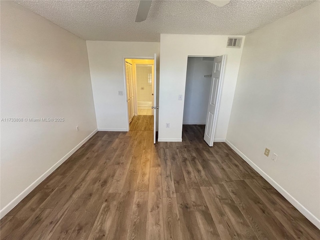 unfurnished bedroom with dark wood-type flooring, ceiling fan, a closet, and a textured ceiling