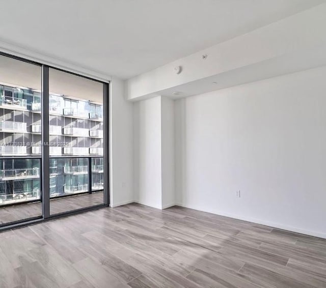 unfurnished room featuring expansive windows, plenty of natural light, and light hardwood / wood-style floors