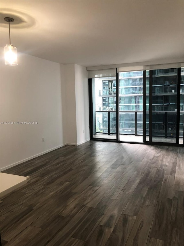 unfurnished room with a wall of windows and dark hardwood / wood-style floors