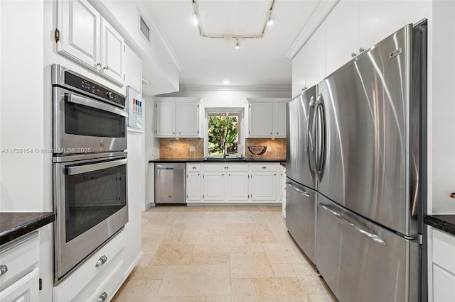 kitchen featuring tasteful backsplash, crown molding, white cabinets, and appliances with stainless steel finishes