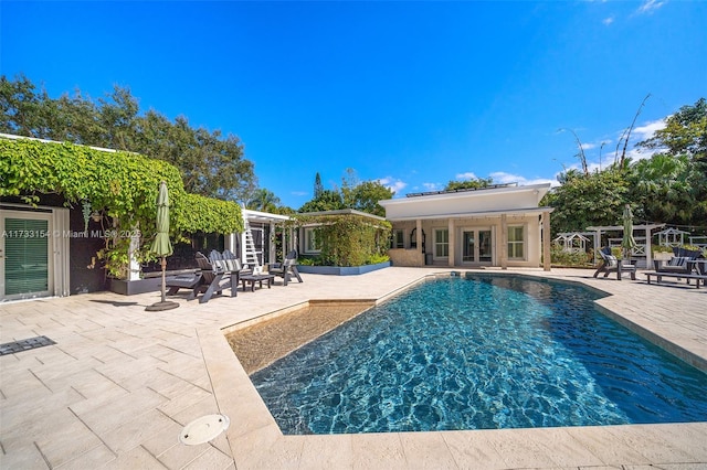 view of swimming pool with french doors, a patio, and an outbuilding