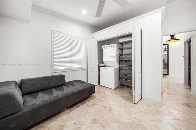 living room featuring ceiling fan, ornamental molding, and stacked washer / dryer