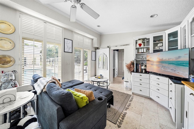 living room featuring ornamental molding, a barn door, ceiling fan, and a textured ceiling