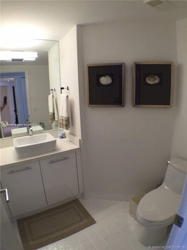 half bathroom featuring baseboards, vanity, and toilet