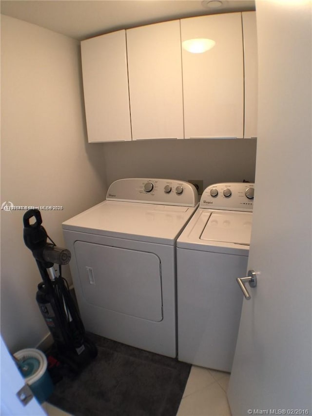 washroom featuring washer and dryer, cabinet space, and light tile patterned floors