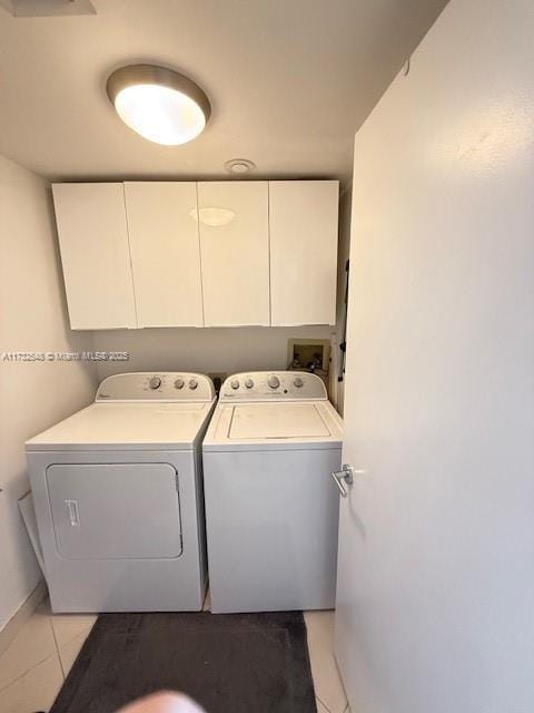 clothes washing area featuring cabinet space, light tile patterned floors, and washer and dryer