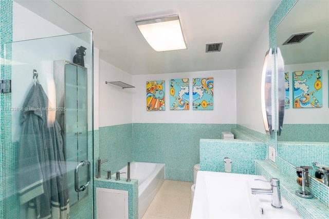 bathroom with toilet, separate shower and tub, tile patterned flooring, and tile walls