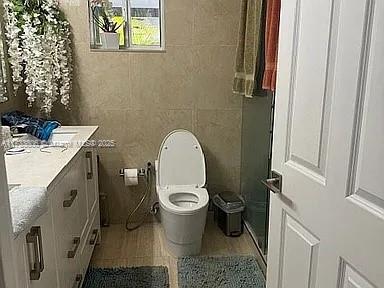 bathroom featuring vanity, tile walls, and toilet