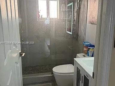 bathroom featuring tiled shower, vanity, and toilet