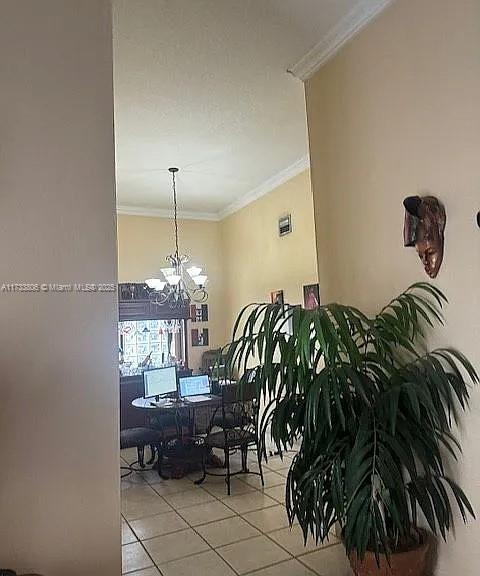 dining room with a notable chandelier, ornamental molding, and light tile patterned flooring