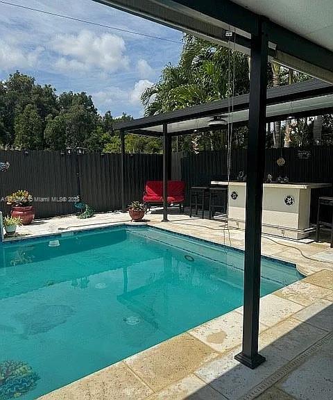 view of swimming pool with a bar and a patio area