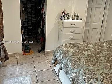 tiled bedroom featuring a spacious closet and a closet