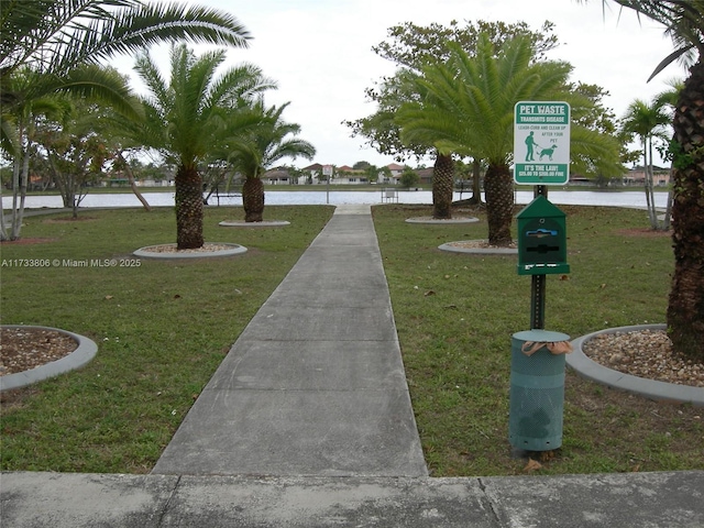 surrounding community with a water view and a lawn