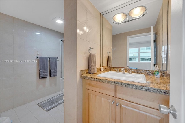 bathroom featuring tile patterned flooring, vanity, tile walls, and walk in shower