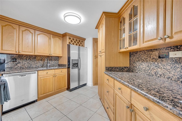 kitchen featuring tasteful backsplash, stainless steel appliances, light tile patterned floors, and dark stone counters