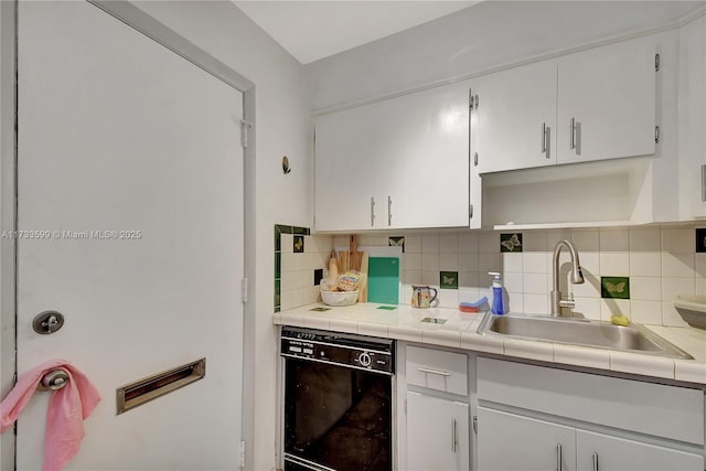 kitchen with dishwasher, sink, tile countertops, and white cabinets