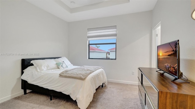 bedroom featuring light colored carpet and a tray ceiling