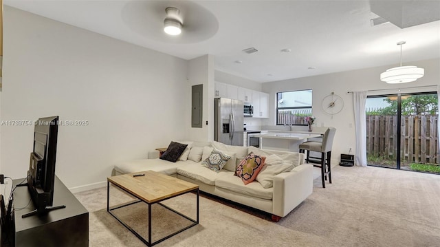 living room with ceiling fan, light colored carpet, and electric panel