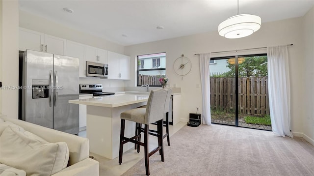 kitchen featuring stainless steel appliances, white cabinets, a kitchen breakfast bar, and decorative light fixtures