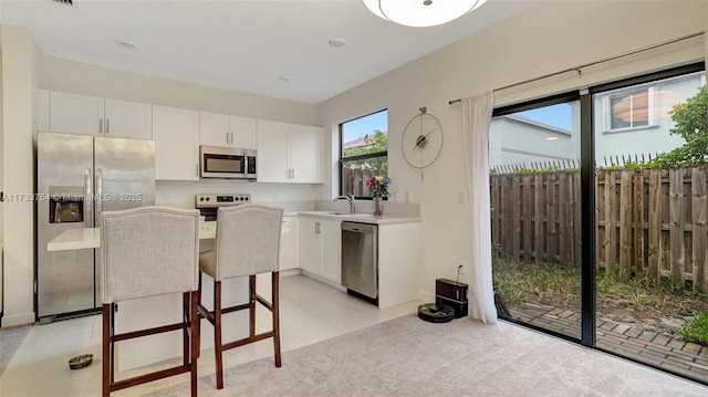 kitchen featuring white cabinetry, stainless steel appliances, a breakfast bar, and sink