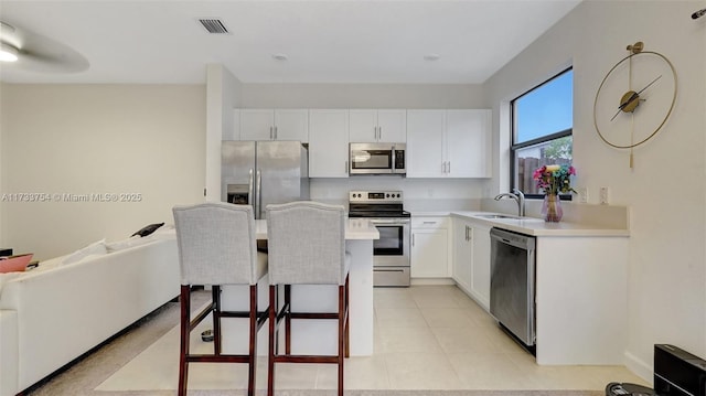 kitchen with white cabinetry, sink, a kitchen breakfast bar, and appliances with stainless steel finishes