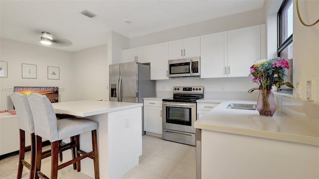 kitchen featuring sink, appliances with stainless steel finishes, a kitchen breakfast bar, a center island, and white cabinets