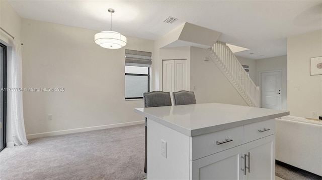 kitchen featuring white cabinetry, hanging light fixtures, light colored carpet, and a kitchen island