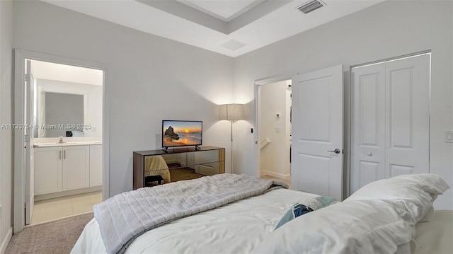 bedroom with light tile patterned floors, ensuite bath, and sink