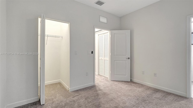 unfurnished bedroom with light colored carpet and a closet