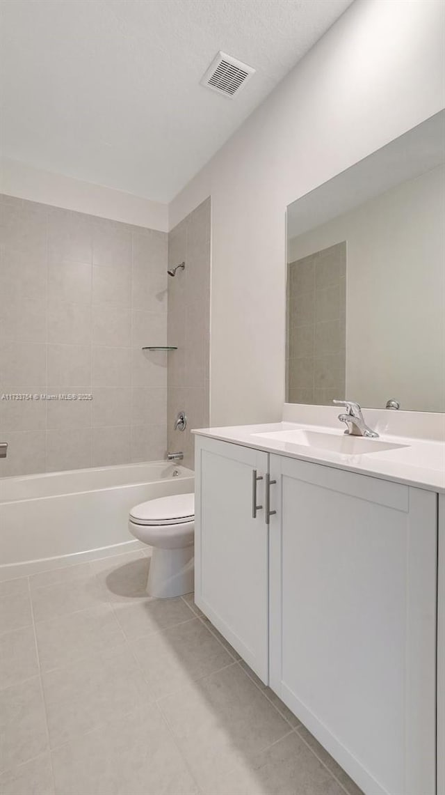 full bathroom with tiled shower / bath, vanity, toilet, and tile patterned floors