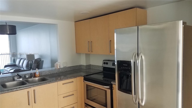 kitchen featuring light brown cabinetry, appliances with stainless steel finishes, dark countertops, and a sink