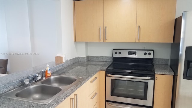 kitchen featuring a peninsula, light brown cabinets, stainless steel appliances, and a sink