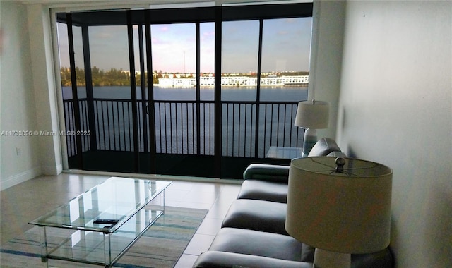 living area with a water view, baseboards, and tile patterned floors