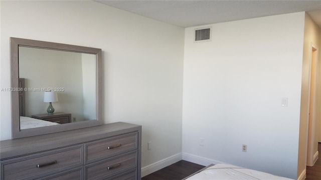 bedroom featuring visible vents, baseboards, and dark wood-type flooring