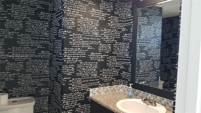 bathroom with tasteful backsplash, vanity, and toilet