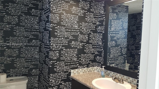 bathroom featuring toilet, tasteful backsplash, and vanity