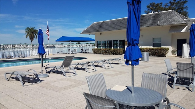 community pool with outdoor dining space, a patio area, and fence