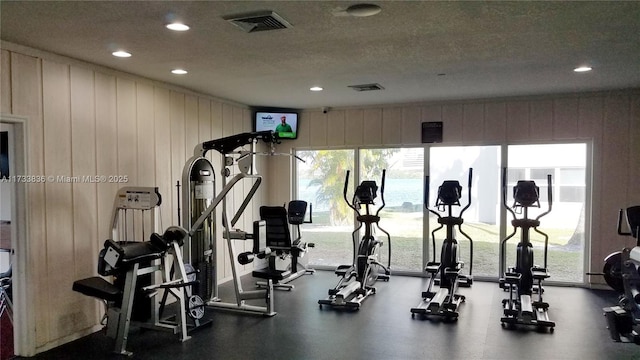 exercise room with a textured ceiling, visible vents, and recessed lighting