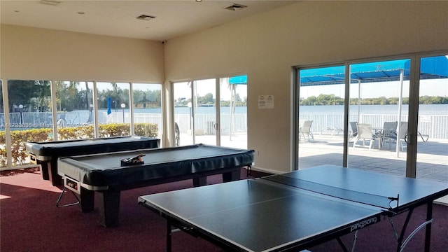 game room with carpet, a water view, and visible vents