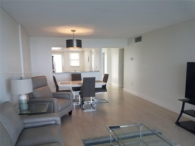 tiled living room featuring a textured ceiling, visible vents, and baseboards