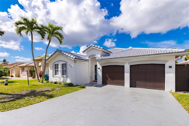 mediterranean / spanish-style home with an attached garage, stucco siding, driveway, and a front yard