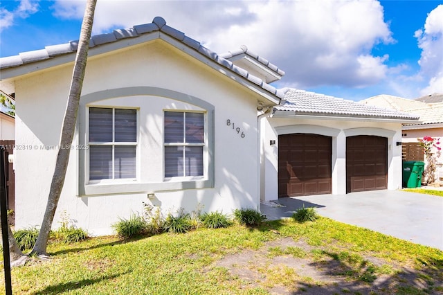 view of front facade with a garage, a tiled roof, concrete driveway, and stucco siding