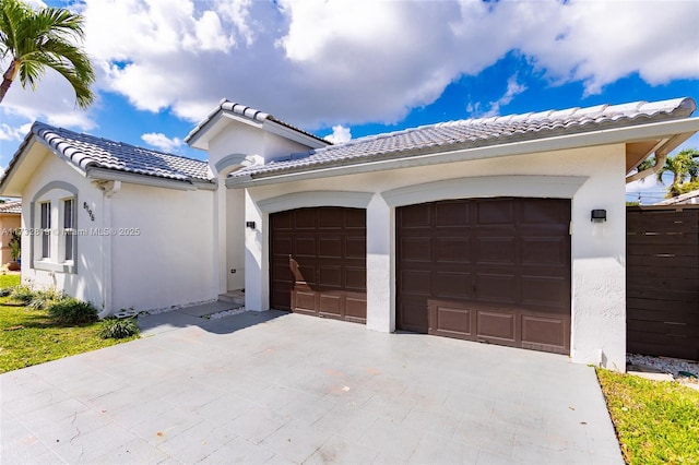 view of front of house featuring driveway, an attached garage, a tile roof, and stucco siding