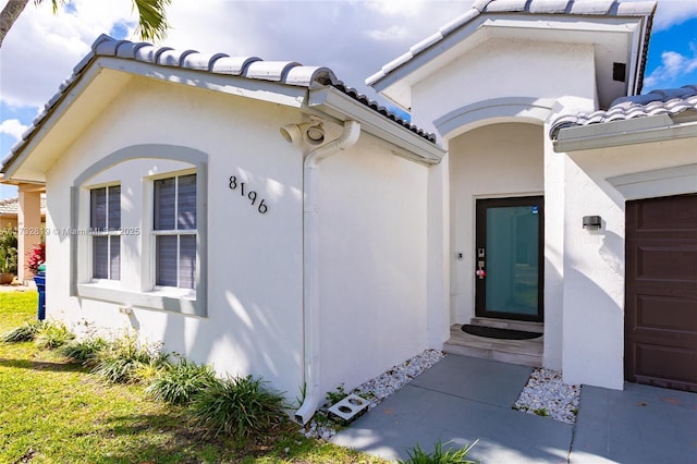 entrance to property with a tile roof and stucco siding