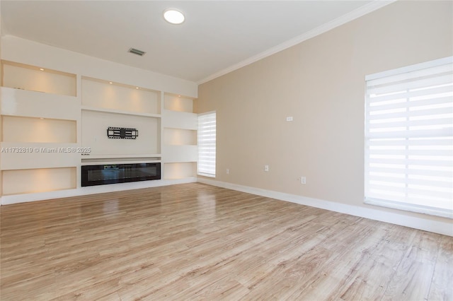 unfurnished living room featuring ornamental molding, light wood-style flooring, a glass covered fireplace, and visible vents